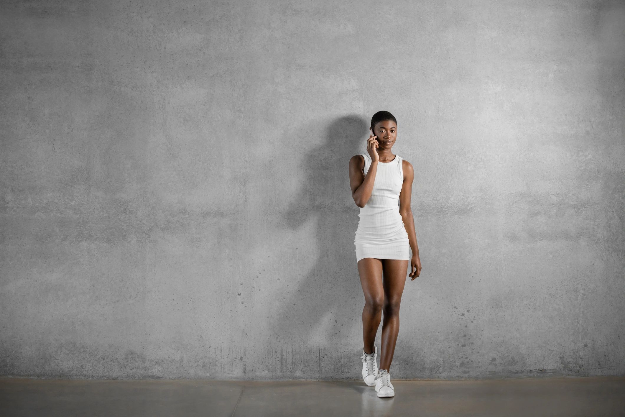 Editorial fashion portrait in a white dress against a modern wall