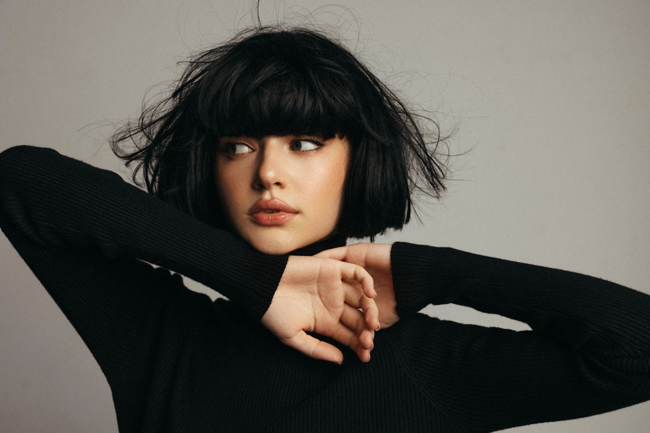 Portrait of a stylish woman with black hair posing in a dark sweater studio shot